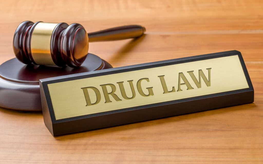 A gavel and a name plate with the engraving Drug law.